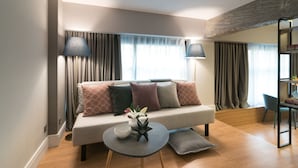 A modern living room with a sofa, two lamps, a small table with decorative items, and a bookshelf. - Lavish Athens Loft | Zephyr Loft | 1 Bedroom | Superb City Views | Prime. (Athens)
