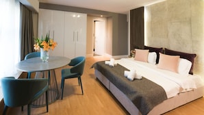 A modern hotel room with a bed, a round dining table with chairs, and a vase of flowers. - Lavish Athens Loft | Zephyr Loft | 1 Bedroom | Superb City Views | Prime. (Athens)