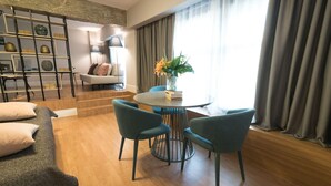 A modern living room with a round table, teal chairs, a sofa, and a decorative shelf. - Lavish Athens Loft | Zephyr Loft | 1 Bedroom | Superb City Views | Prime. (Athens)