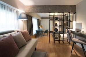 A modern living room with a sofa, a dining area with chairs, a table, and a bookshelf.