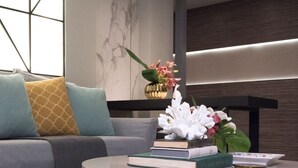 A modern living room with a grey sofa, a round coffee table, and a bookshelf. - Alluring Athens Maisonette | Apollo Heights Maisonette | 1 Bedroom | Superb. (Athens)