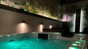 A hot tub with a stone wall and plants above it. - Alluring Athens Maisonette | Apollo Heights Maisonette | 1 Bedroom | Superb. (Athens)