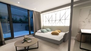 A modern bedroom with a large bed, a small round table, and a view of the outdoors through a sliding glass door. - Alluring Athens Maisonette | Apollo Heights Maisonette | 1 Bedroom | Superb. (Athens)