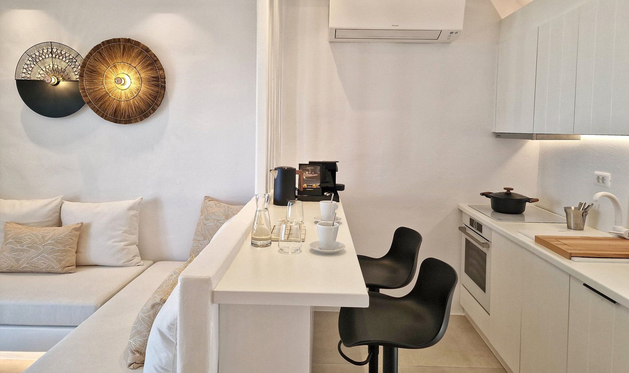 Una cocina moderna con una isla central, una cafetera y un área de comedor con sofá y sillas.