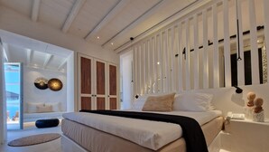Un dormitorio moderno con una cama grande, una mesita de noche con lámpara y vistas al exterior.
