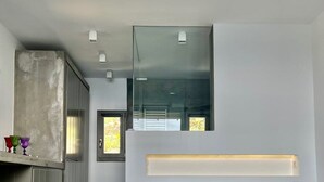 A modern bedroom with a large bed, a concrete cabinet, and a large window. - Thrilling Tinos See Front Studio | Zoi Studio | Breathtaking Sea Views |. (Tinos)