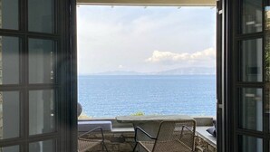 An open balcony with a view of the sea, a bed, and two wicker chairs. - Thrilling Tinos See Front Studio | Zoi Studio | Breathtaking Sea Views |. (Tinos)
