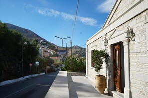 Una calle con un edificio que tiene una planta grande en maceta y una puerta de madera.