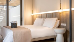 Habitación de hotel moderna con cama, mesita de noche y vistas a través de un ventanal.