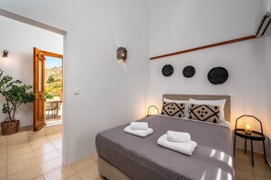 Ein Schlafzimmer mit einem Bett, zwei Wandleuchten, einem Holzbalken an der Decke und drei dekorativen Gegenständen an der Wand.