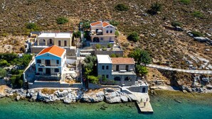 A coastal property with multiple buildings, clear turquoise waters, and rocky terrain. - Superb Symi Villa | Villa Elysian Blue | 4 Bedrooms | Breathtaking Sea Views |. (Symi)