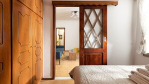 Ein Schlafzimmer mit Holzschrank, Bett mit Steppdecke und einer Tür zu einem anderen Raum.