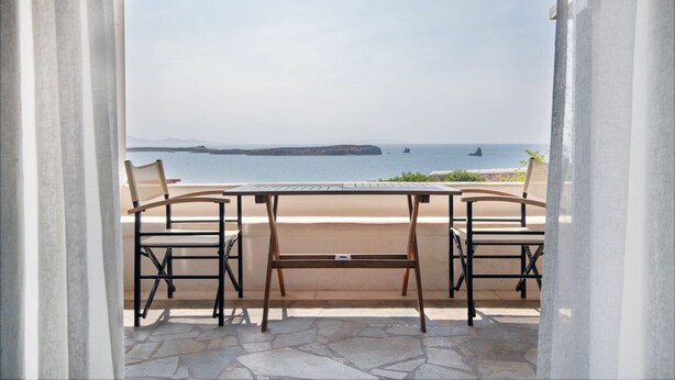 Eine Terrasse mit Tisch und Stühlen mit Blick auf die Küste.