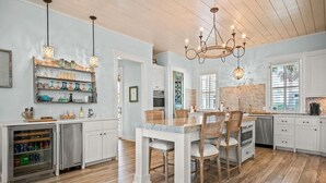 Una cocina con armarios blancos, una mesa de comedor de madera y un candelabro.