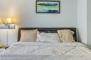 Un lit bien fait, avec une couverture matelassée, une tête de lit et deux coussins décoratifs.