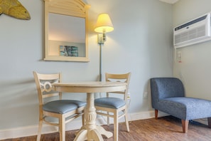 A room with a round table, two chairs, a lamp, a mirror, and an air conditioning unit. - Ocean-view Balcony! Couples Escape in Myrtle Beach (Myrtle Beach)