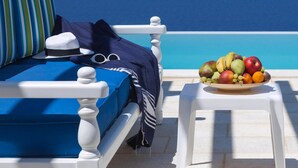 Eine sonnendurchflutete Terrasse mit einem weißen Stuhl, einem blauen Sofa und einer Obstschale.