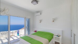Ein Schlafzimmer mit Bett, Nachttisch und Meerblick.