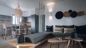 Uma sala de estar moderna com sofá modular, mesa de centro de madeira e um espaço de jantar com cadeiras de madeira.