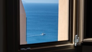 Blick auf den Ozean durch ein Fenster, ein Schiff ist in der Ferne sichtbar.