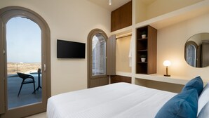 Ein Hotelzimmer mit Bett, Wandfernseher, Schreibtisch mit Stuhl und Blick ins Freie.