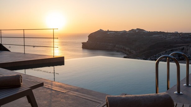 Ein Infinity-Pool mit Blick auf das Meer und eine Klippe bei Sonnenuntergang.