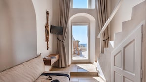 A hotel room with a bed, a TV, a window with curtains, and a view of the outside.