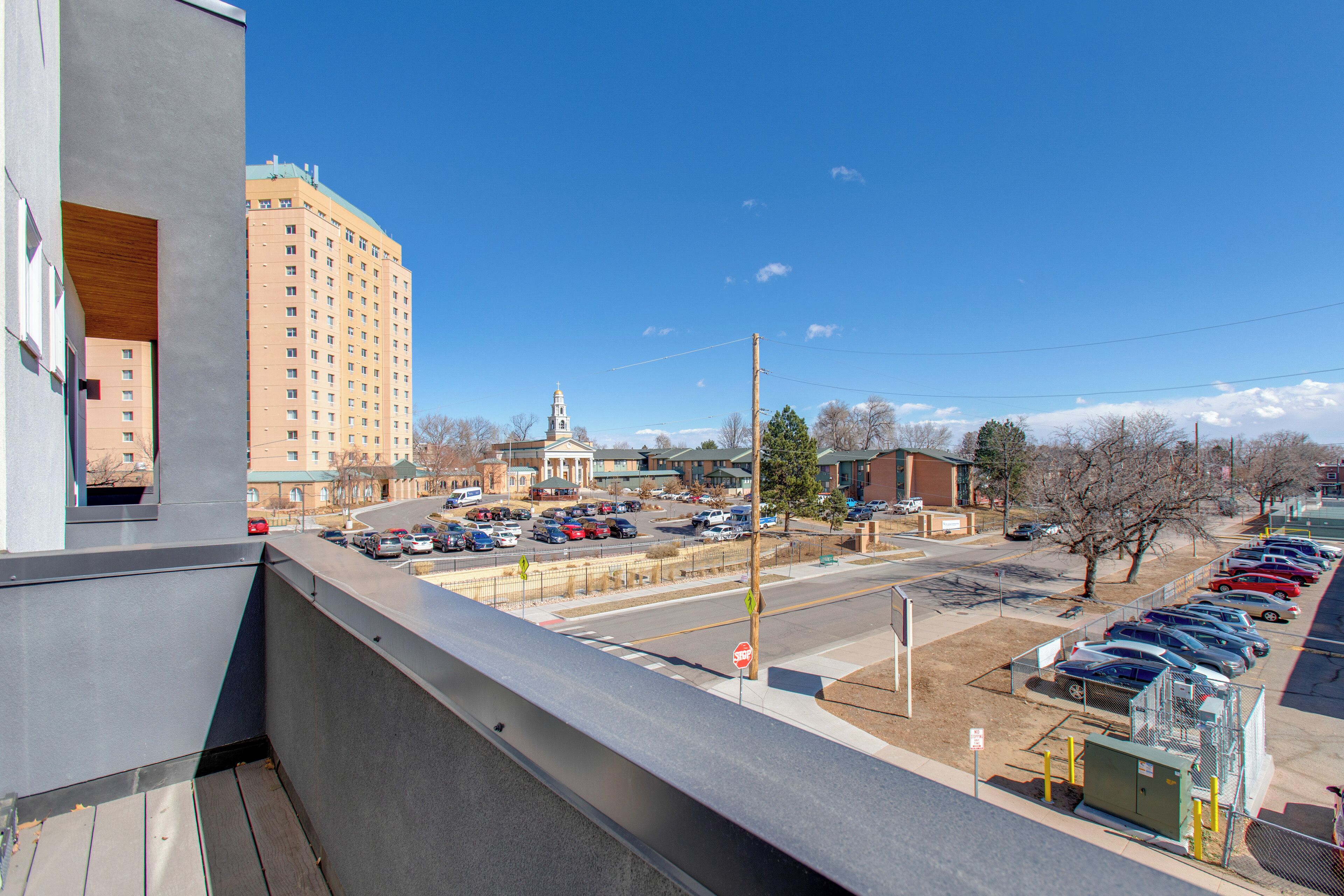 A parking lot with multiple cars, a building with a dome, and a clear blue sky.