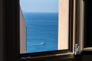 A view of the ocean through a window, with a boat visible in the distance. - Villa Eunomia, 2 BDR, Wonderful Seaviews, Private Pool, Santorini (Santorini)