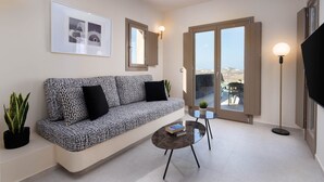Ein modernes Wohnzimmer mit einem gemusterten Sofa, einem Couchtisch, einem gerahmten Bild und Blick durch eine Glastür.