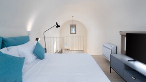 Ein Schlafzimmer mit einem Bett, einem Fernseher, einem Schreibtisch und einem Fenster.
