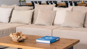 A modern living room with a sectional sofa, a wooden coffee table, and pendant lights. - Superb Seafront Mykonos Villa | Villa Eros | 4 Bedrooms | Panoramic Sea Views |. (Mykonos)