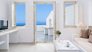 Une chambre moderne et minimaliste, dotée d’une grande fenêtre offrant une vue sur la mer et les montagnes.