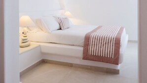 Une chambre à coucher au style minimaliste, avec un lit blanc, une lampe de chevet et une petite fenêtre.