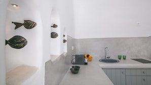 A modern kitchen with a sink, two bowls, a fruit bowl, and decorative fish on the wall. - Villa Ioneira, Sea Views, Outdoor Hot Tub, Furnished Terrace, Santorini (Santorini)