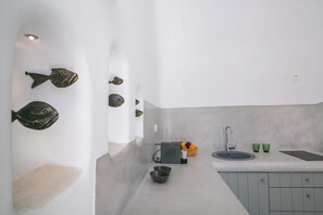Una cuina moderna amb un obrador, dues safates, un plat de fruita i peixos decoratius a la paret.