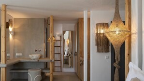Une salle de bain moderne avec un lavabo en pierre, des éléments décoratifs en bois et un luminaire suspendu original.