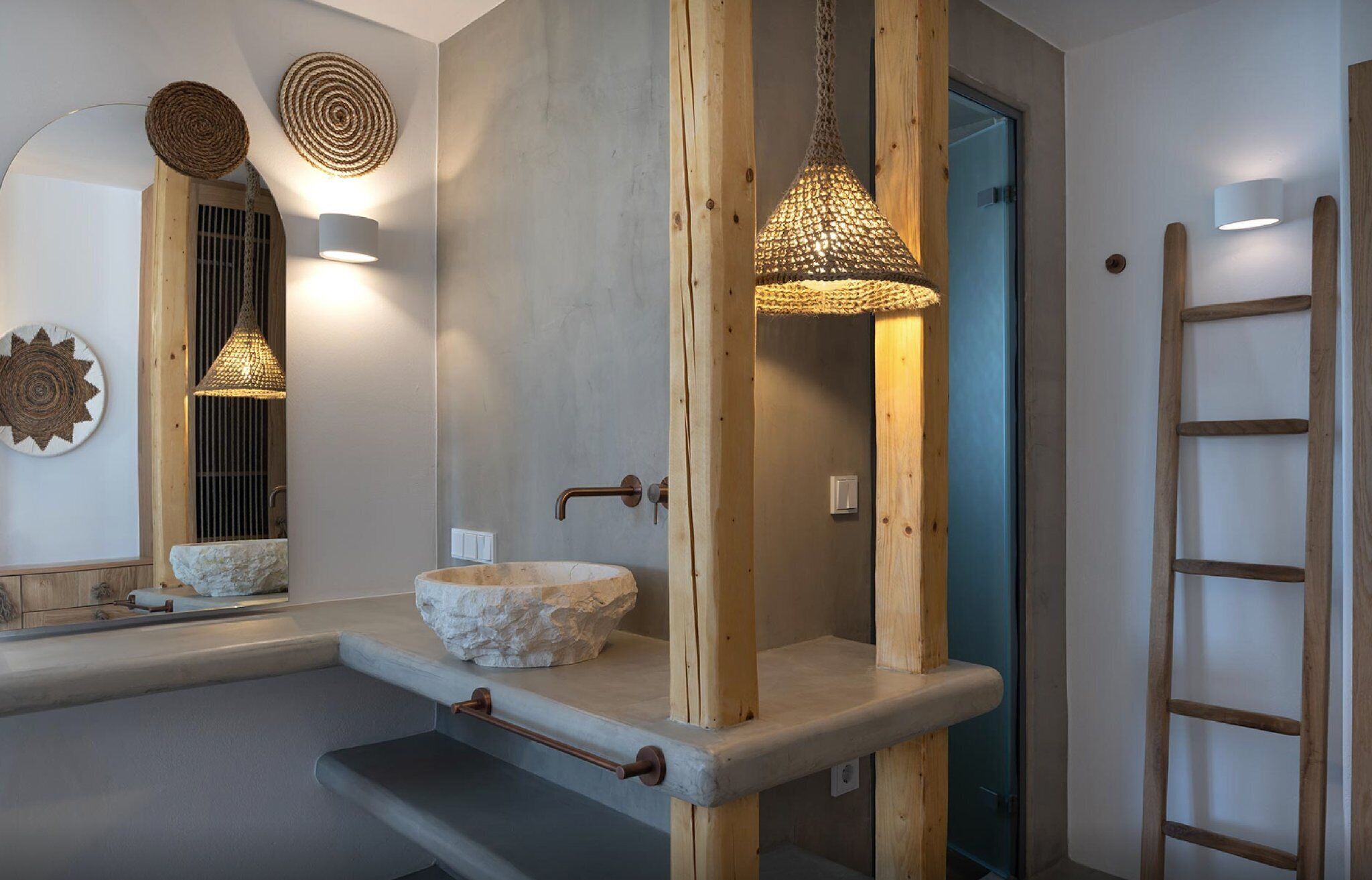 Un bagno con lavabo in pietra, travi in legno e lampadari in vimini.