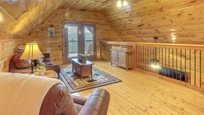 Una sala de estar acogedora con piso de madera, un ventilador de techo, un sofá, una mesa de centro y una lámpara.