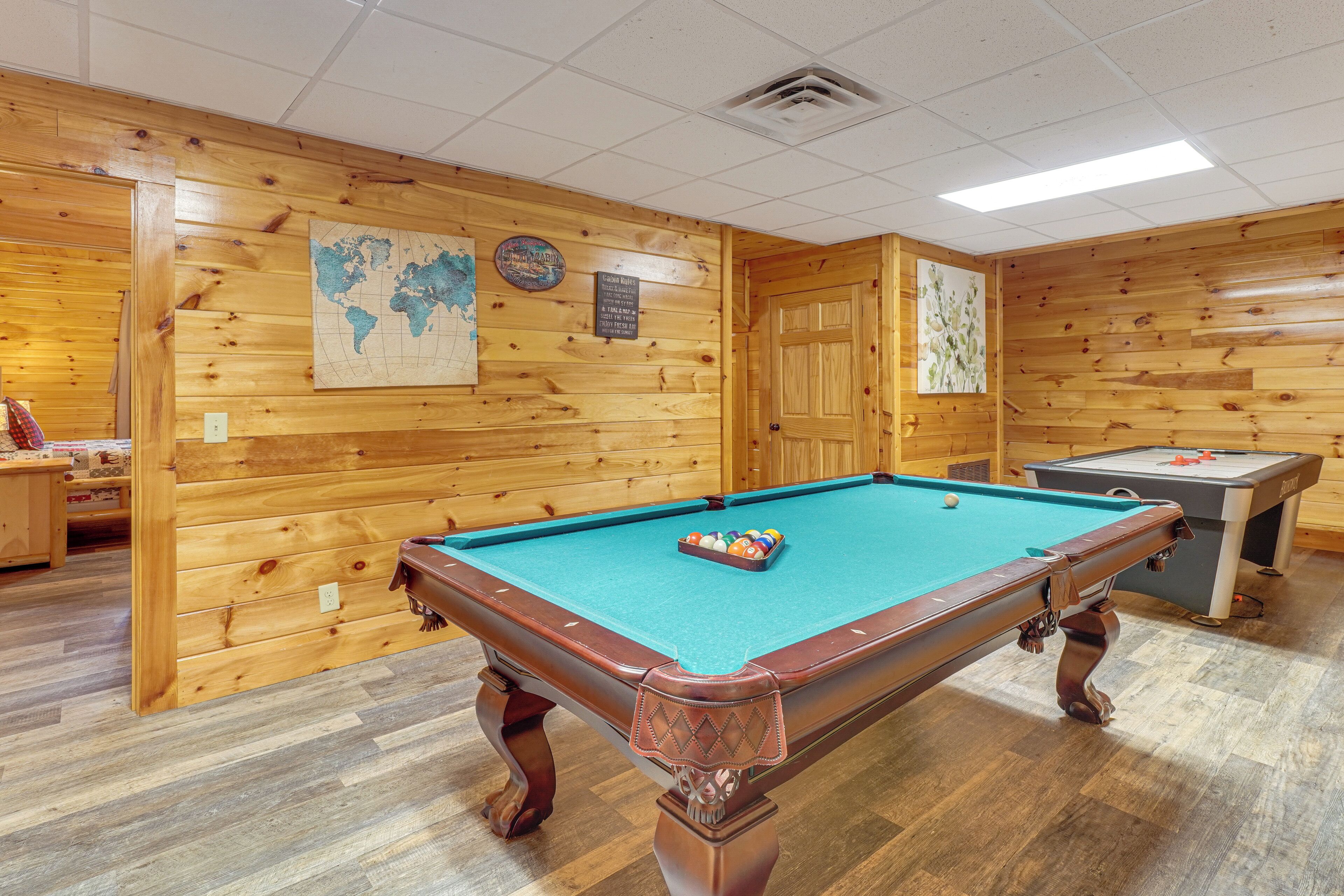 A pool table with balls, a billiards table, and a world map on the wall.