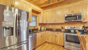Una cocina moderna con electrodomésticos de acero inoxidable, armarios de madera y encimera de granito.