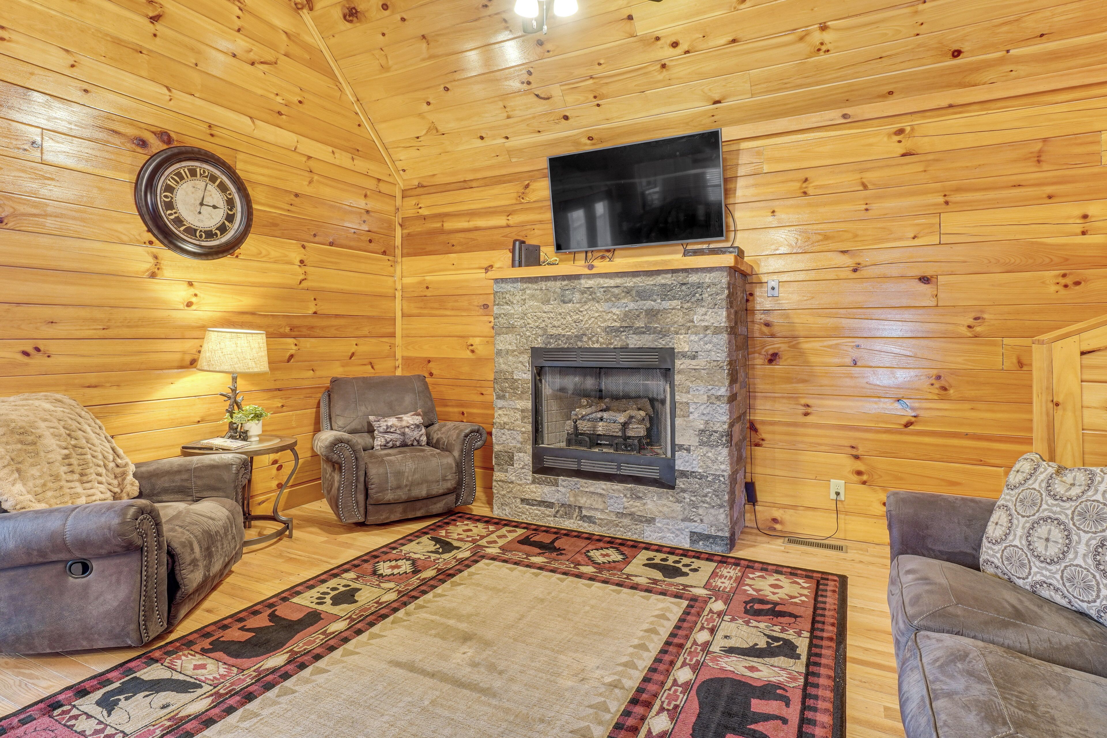 L’intérieur d’un chalet confortable, avec une cheminée, deux canapés en cuir, un tapis à motifs et une horloge murale.