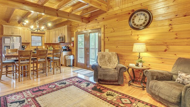 Interior espacioso de una cabaña de madera, con comedor, zona de estar acogedora y cocina.