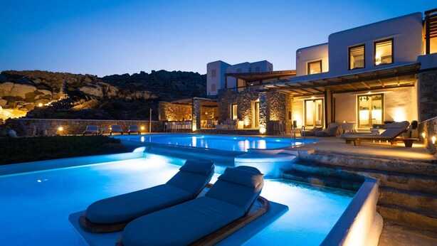 Ein moderner Poolbereich mit Liegestühlen und einer Steinmauer.