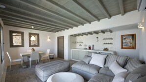 Ein modernes Wohnzimmer mit einer Eckcouch, einem Essbereich mit Tisch und Stühlen sowie einer Küchenzeile mit Schränken und Arbeitsplatte.