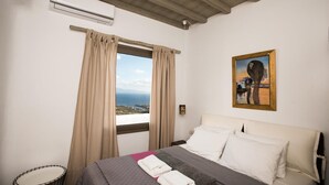 Ein Hotelzimmer mit Bett, Blick auf das Meer und einem Gemälde an der Wand.