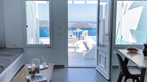Une chambre avec vue sur la mer, un coin repas avec une table et des chaises, et un espace salon confortable avec un canapé.