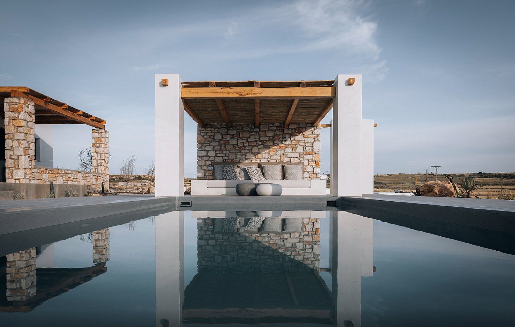A modern outdoor pool area with stone walls and a wooden deck.