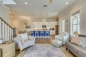 A spacious living area with a sofa, armchairs, and a coffee table. A kitchen with a bar and island is visible in the background. - Steps to 30A Beaches! 4BR Coastal Home - Sleeps 12 (Santa Rosa Beach)