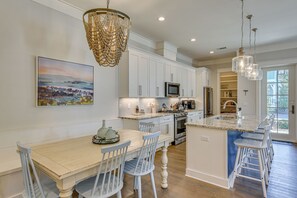A modern kitchen with white cabinetry, a central island with bar stools, a chandelier, and a painting on the wall. - Steps to 30A Beaches! 4BR Coastal Home - Sleeps 12 (Santa Rosa Beach)